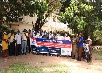 Minority Rights Group: a group of people hold a banner at a community awareness meeting