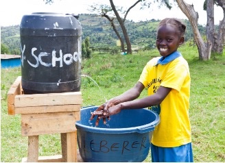 Friends of Kipkelion: young girl smiles while washing her hands from tippy tap
